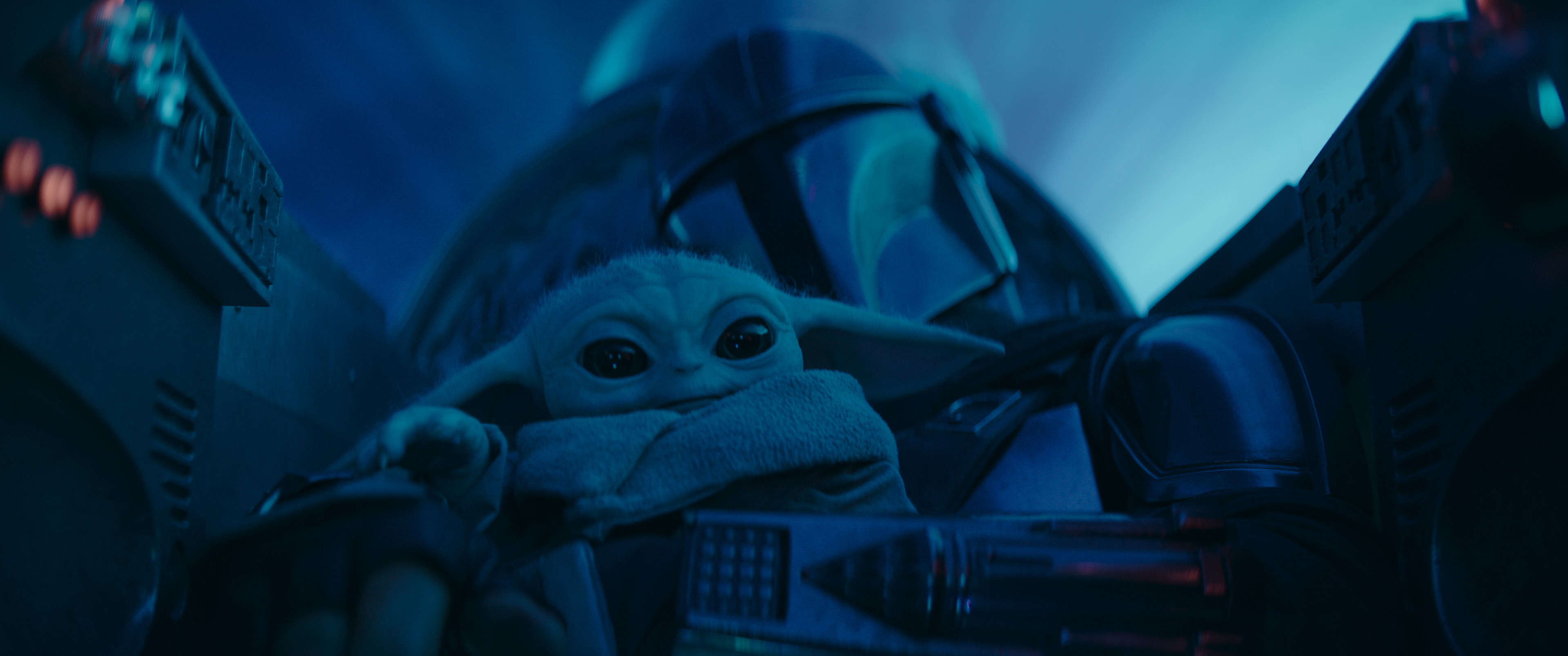 Mando accompanied by "Baby Yoda" on board his ship. Image from the series The Mandalorian on Disney+.